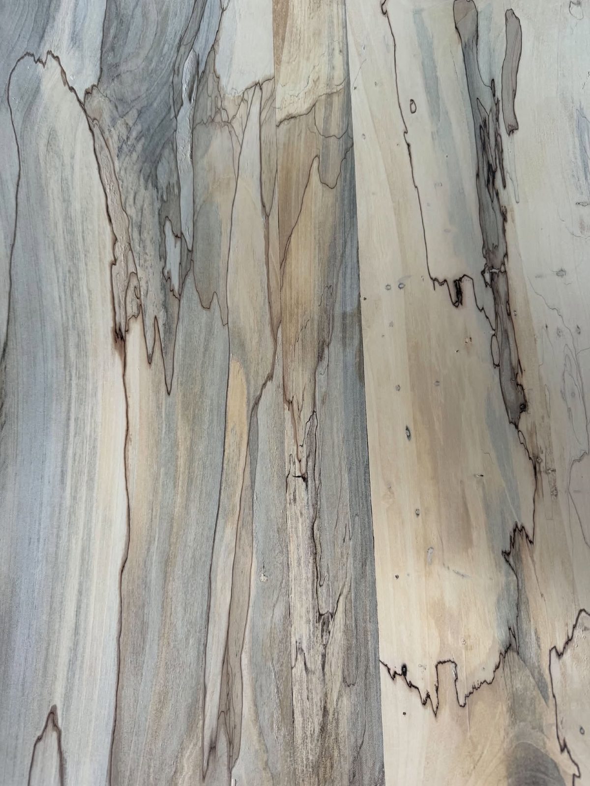 Planed magnolia boards heavily spalted, with black fungal zone lines and blue-grey staining running through pale sapwood.